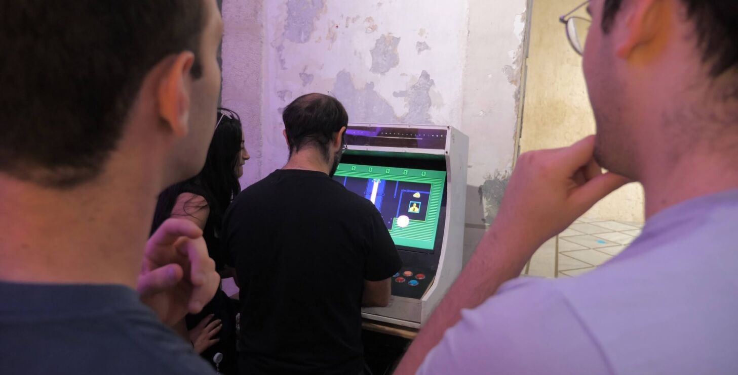 Onlookers watching a player at the arcade cabinet